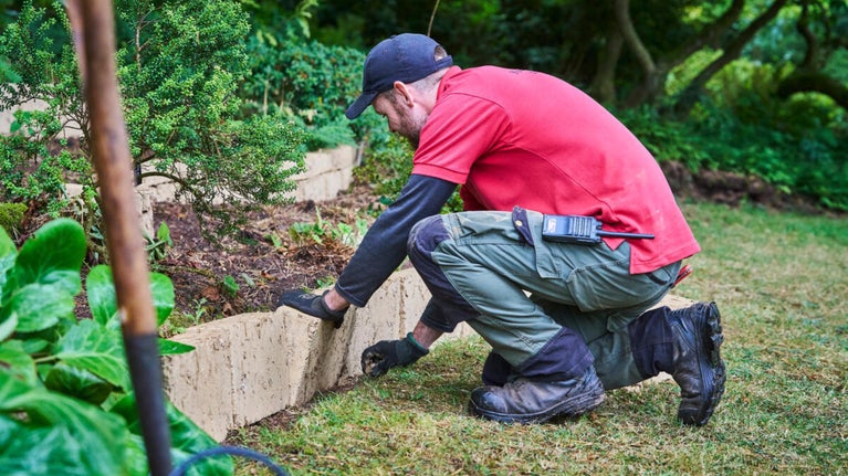 Gardener restoring the Garden in the Wood with cob blocks
